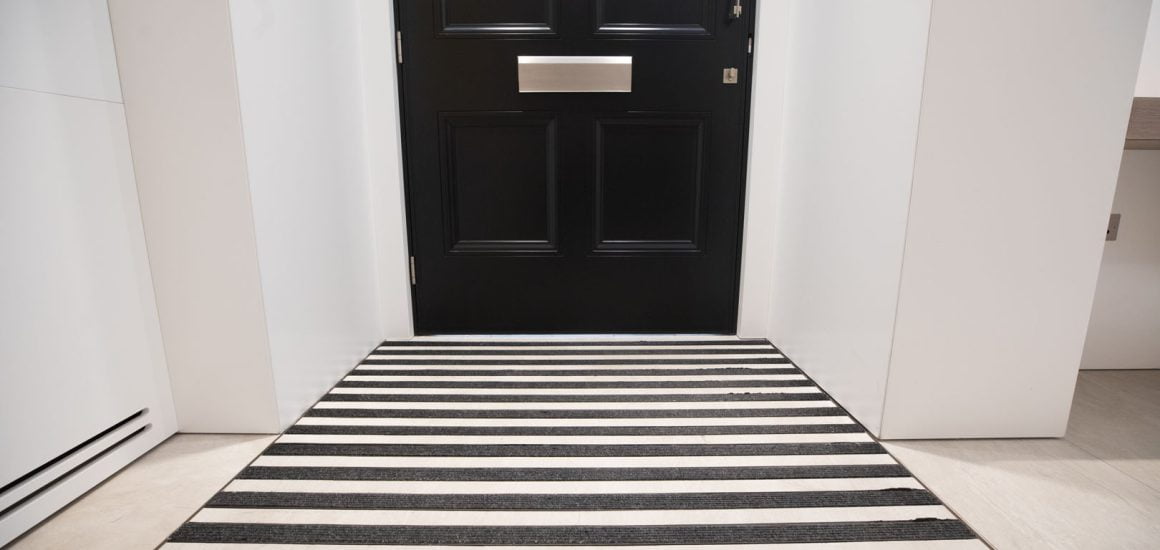 image showing a black door and entrance matting in strips at a commercial office building