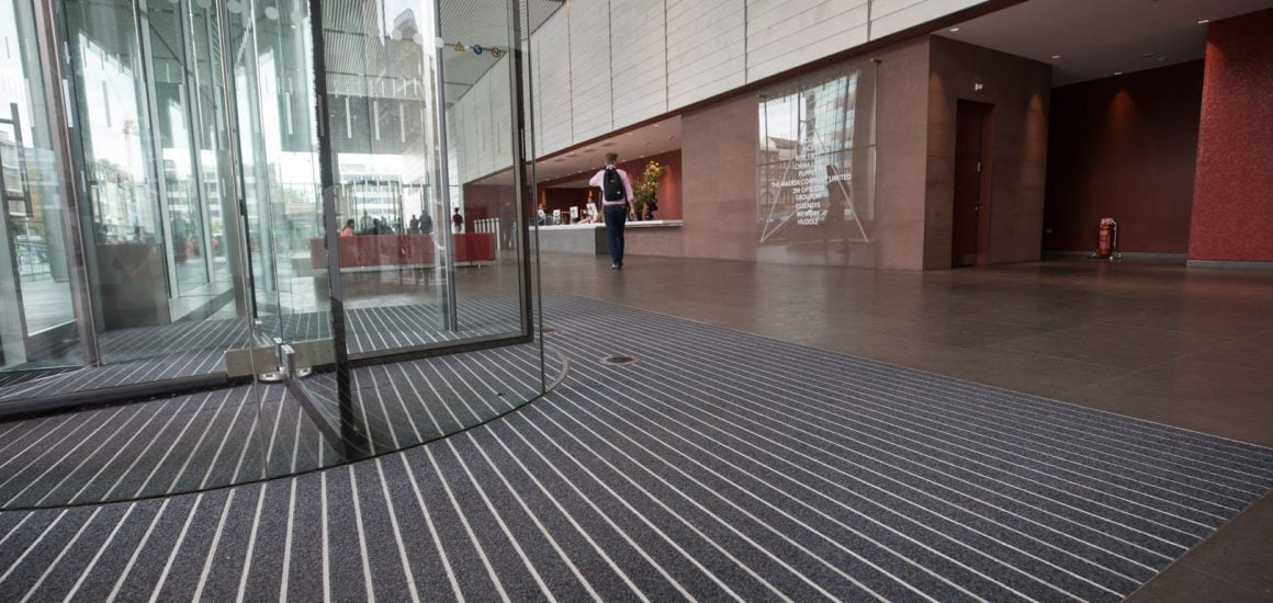 Image showing a revolving door with grey fibre entrance matting in the reception of a commercial office building